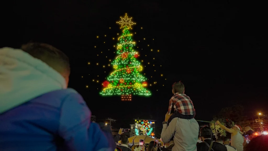 personas viendo el árbol de show de drones